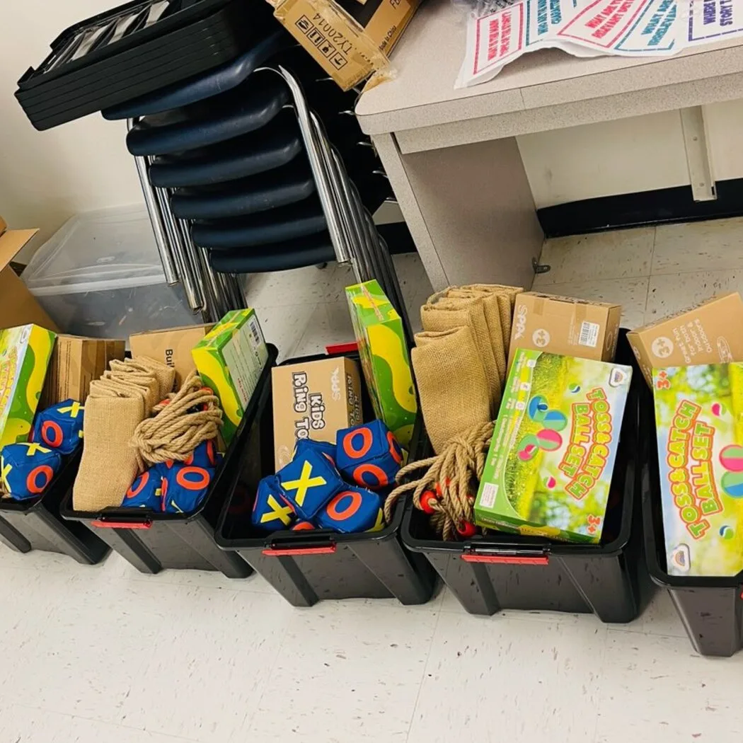 Bins of new playground equipment, including toss and catch sets, ring toss games, jump ropes and bean bags, ready for delivery to a Winter Haven school